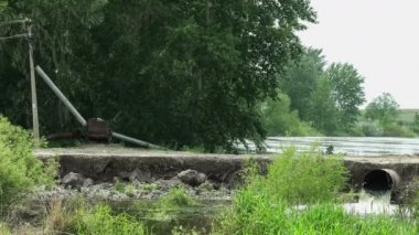 Suyla yıkanmış yol. Yaz mevsimsel nehir seli. Su akıyor. Güneşli bir günde kırsal doğa manzarası.