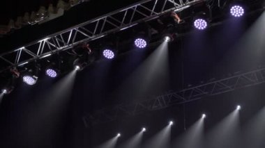 Renkli projektörler bir müzik çiftliğinde asılı. Konser salonunda ışıklar dönüyor ve parıldıyor. Otomatik ışıklandırma sahne teknolojisi.
