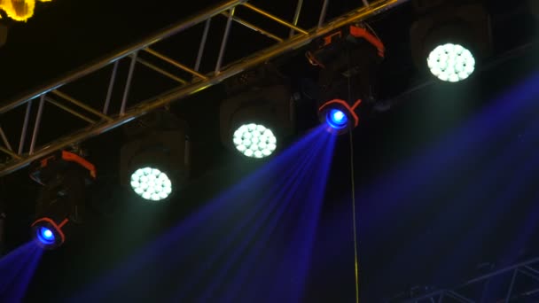 Kleurrijke projectoren hangen op een muzikale boerderij. Spotlights draaien en glinsteren in de concertzaal. Automatische verlichtingstechnologie. — Stockvideo