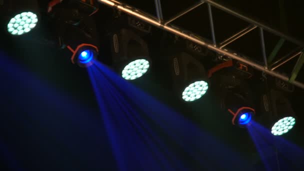 Färgglada projektorer hänger på en musikgård. Spotlights roterar och skimrar i konsertsalen. Automatiserad ljussättningsteknik. — Stockvideo
