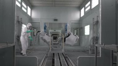 Koşu bandındaki araç parçalarını boyamak. Araba üretim fabrikası. Otomobil boyacısı çarpışan bir arabaya kırmızı boya sıkıyor..