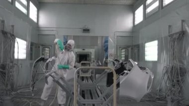 Koşu bandındaki araç parçalarını boyamak. Araba üretim fabrikası. Otomobil boyacısı çarpışan bir arabaya kırmızı boya sıkıyor..
