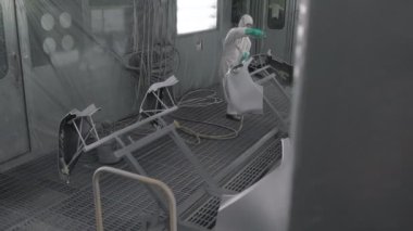 Koşu bandındaki araç parçalarını boyamak. Araba üretim fabrikası. Otomobil boyacısı çarpışan bir arabaya kırmızı boya sıkıyor..