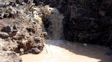 Kahverengi çamur su üzerinde ve taşlar arasında çalışan