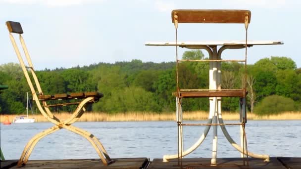 Металлический стол и два старых стула на деревянном причале — стоковое видео