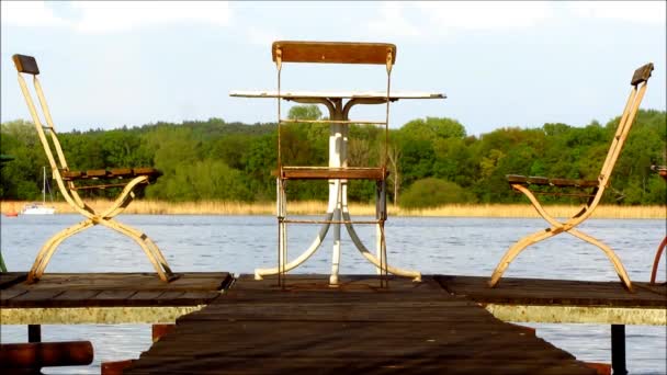 Three old metal chairs and table on jetty — Stock Video