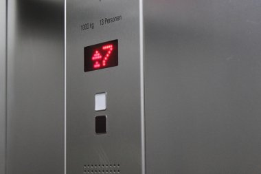 Yedinci kata ulaştığını belirten bir asansör görüntüleme. Gösteren sayı yedi ve okları kırmızı yanar.