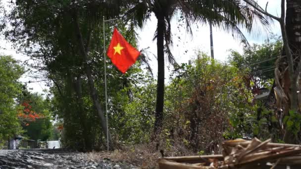 Σημαία του Βιετνάμ κυματίζει στην κοντάρι σημαίας ενώ μηχανάκι οδήγηση κάτω από το δρόμο δίπλα — Αρχείο Βίντεο