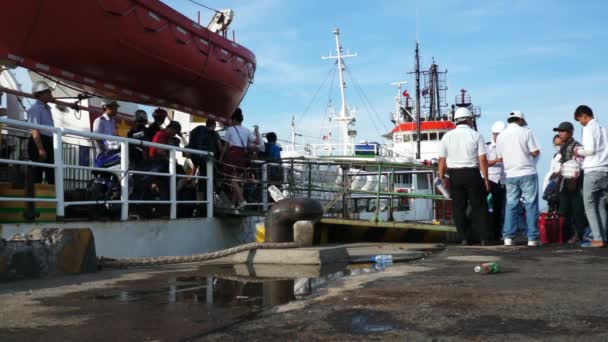 Personer ombord fartyget att ön Con Dao i hamnen. Flera personer, delar av båten och en röd räddningsbåt synliga. — Stockvideo