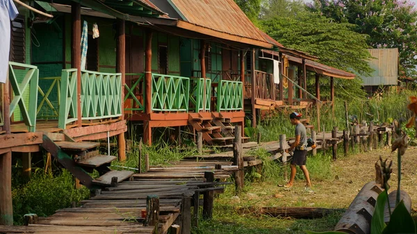 Genç bahçıvan kesme ot ahşap tatil bungalov önünde fırça kesici ile.