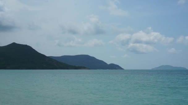 Oceano azul em frente às montanhas e algumas nuvens no céu . — Vídeo de Stock