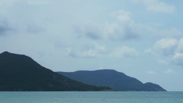 Kamerafahrt von blauem Meer vor Bergen und ein paar Wolken am Himmel. — Stockvideo