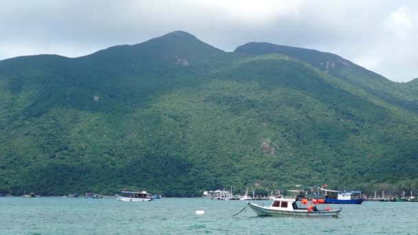 大きな山の風景の前に静かな湾で横になっている小型のボート — ストック動画