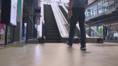 Genç adamın yürüyen merdivenlerde, modern yürüyen merdivenlerde ilerlerken yakın plan fotoğrafı..