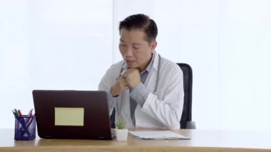 Doktor laptopta video görüşmesi yapan bir hastayla konuşuyor. İnternetteki web kamerasıyla iletişim kuran bilgisayar ekranına bakan doktor erkek konuşuyor. Teletıp kavramı