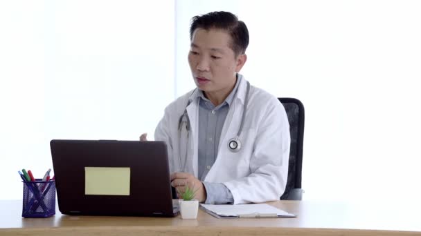 ノートパソコンでビデオ通話をしてる患者と話してる 医師男性はPc画面を見て話すウェブチャットの顧客とオンラインでウェブカメラで通信しています テレメディシンの概念 — ストック動画