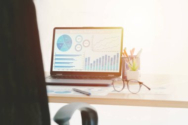 Laptop iş analiz planı ekran ve kağıt grafiği ahşap masa üzerinde