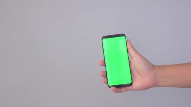 Erkeklerin elindeki boş dijital akıllı telefon, Gri izole arkaplanda cep telefonu yeşil ekran