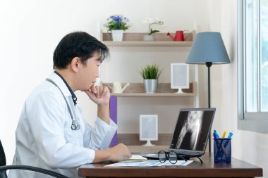 Doktor dizüstü bilgisayardan röntgen sonuçlarını kontrol ediyor. Doktor Xray sonuçlarını çevrimiçi okumak için dijital akıllı cihaz kullanıyor. Modern teknoloji