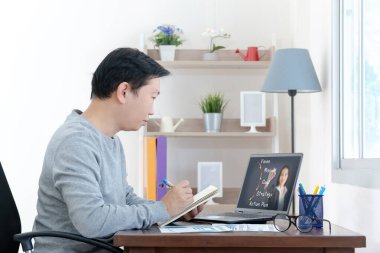 İş adamı el yazısı masasında oturup webinar izliyor ya da dizüstü bilgisayar eğitimi alıyor, evde bilgisayar eğitimi almakla meşgul.