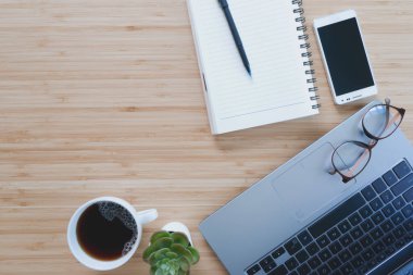 Evden çalışıyorum. Masasında dizüstü bilgisayarı, boş not defteri, sehpanın üzerinde kahve fincanı ve kalem vardı. Düz görünüm kopyalama aralığı.