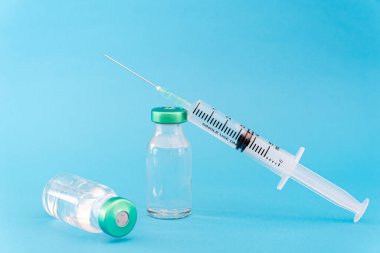 Mavi arka planda potansiyel deneme aşaması konsepti. Şişeleri steril şırıngayla kapatın. Araştırma ve Geliştirme, Aşılama Konsepti.