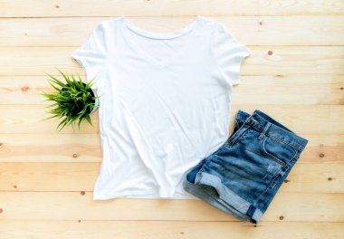 Beyaz tişört modeli ve kahverengi ahşap arka planda kısa kot. Şablon, düz yat 