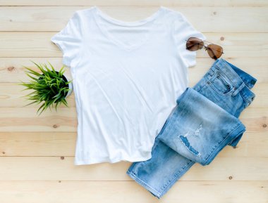 Kahverengi ahşap arka planda beyaz t-shirt model kot ve güneş gözlüğü. Şablon, düz yat