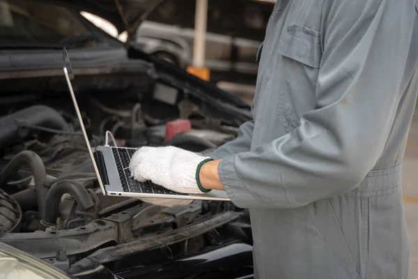 Wykwalifikowany Mechanik Korzystający Laptopa Sprawdzania Informacji Podczas Pracy Silnika Samochodowego — Zdjęcie stockowe