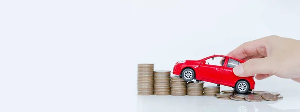 Business man and close up hand holding model of toy car red on over a lot money of stacked coins - insurance, loan and buying car finance concept. buy and installments down payment a car