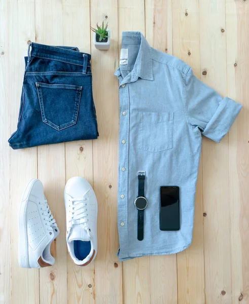 Ahşap zeminde erkek kıyafetleri ve eşyalar var.