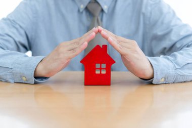 Asyalı işadamı elleri kırmızı ev model konut konutlarını koruyor ev koruması, sigorta, gayrimenkul yatırımları. Beyaz arkaplan