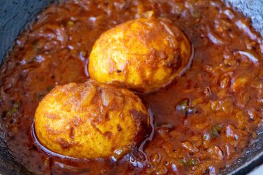 Anda Curry ya da Dim Bhuna olarak bilinen lezzetli ve geleneksel Bengali yemeği, baharatlı Masala Curry yumurtasının yakın çekimi. Haşlanmış yumurta, zengin, kalın, kırmızımsı kahverengi sosta pişirilmiş. Hint yemeği..