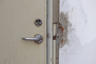 Modern Door Lever Set ve açıkta bırakılmış mekanik kapı kilidi silindiri (anahtar silindiri, kilit çekirdeği) içeren yeni bir çelik kapı kurulumunun yakın çekimi. Bitmemiş beton duvarın bitirilmesi gerekiyor.