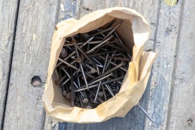 İçinde büyük miktarda Sinker Coated Steel Nails bulunan kahverengi bir kesekağıdının üst görüntüsü. İnşaat ve ahşap endüstrisinde yaygın olarak kullanılan ince metal bağlayıcılar. Donanım arkaplanı.