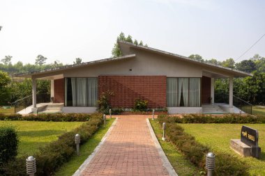 3 Aralık 2025 'te Shaldah Eco Resort, Gazipur, Bangladeş' te bulunan 'PARULI' konutunun dış görünüşü, tuğla işçiliği ve alçak eğimli çatı hattını birleştiren modern bir tek katlı bina..