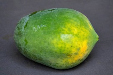 Temiz bir arkaplanda taze olgun bir papaya meyvesinin yakın çekimi. Sağlıklı beslenmenin, vitamin zengini tropikal meyvelerin ve dengeli beslenmenin doğal bileşenlerinin güzel bir temsili..