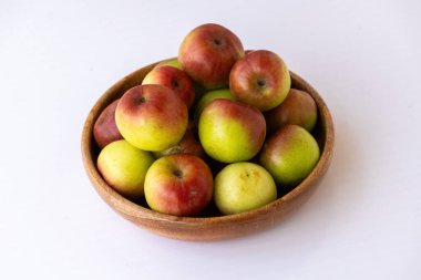 Taze olgun jujube meyveleri (Ziziphus mauritiana) beyaz arka planda tahta bir kase içinde. Kırmızı ve yeşil derili bir grup Çinli sağlıklı organik atıştırmalık ve bitkisel ilaç olarak kullanılır.
