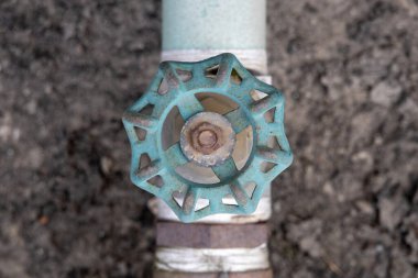 Tesisat borusuna takılmış eski bir deniz mavisi kapakçığı kabzasının yakın çekim görüntüsü. Endüstriyel hizmet temaları, konut su kontrol sistemleri ve ev onarımı için ideal