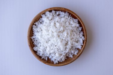 Tahta bir kasede parçalanmış hindistan cevizi etinin yüksek açılı görüntüsü. Taze rendelenmiş organik hindistancevizi, sağlıklı pişirme için ham tropikal bir gıda bileşeni, beyaz arka planda izole edilmiş.