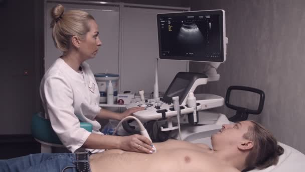 Blonde doctor talking to a patient while doing ultrasonography — Stock Video