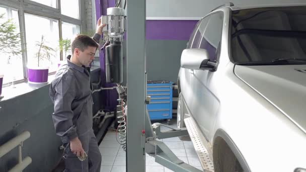 Reparateur drückt Taste, um das Auto zu heben — Stockvideo