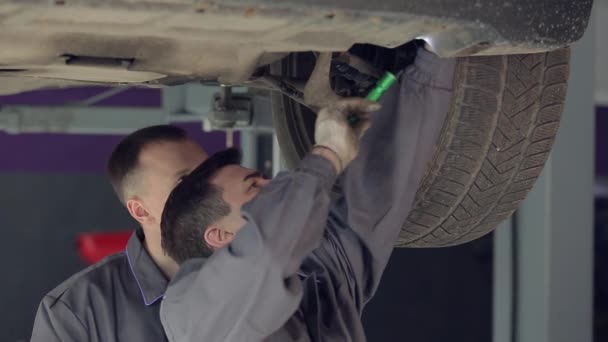 Dos hombres en servicio de coche comprobando la parte inferior del coche — Vídeos de Stock