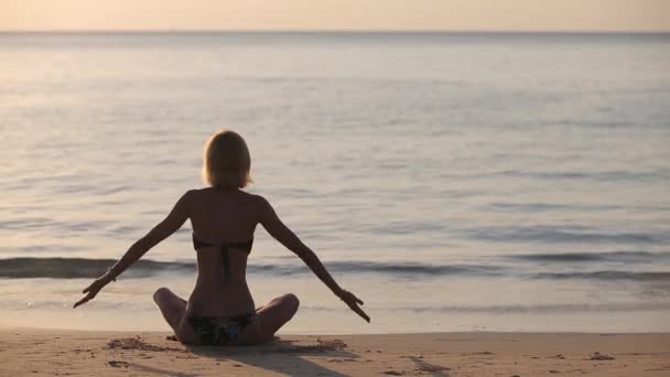 Ung kvinna utövar yoga på stranden — Stockvideo