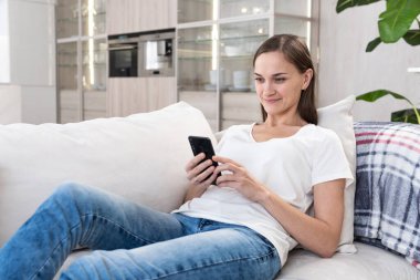 Kadın kanepede akıllı telefon kullanıyor.