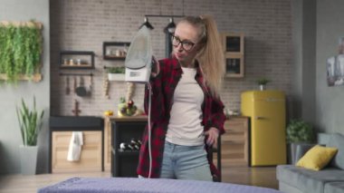 Kadın ütü yaparken dans ediyor.