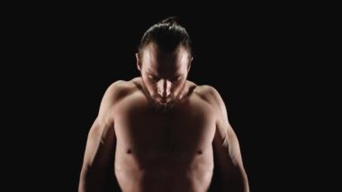 Atletik bir adam kameraya bakıyor.