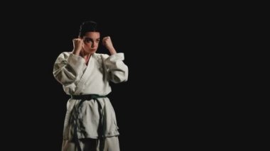 Kimonolu genç kadın karate tekmeleri uyguluyor.