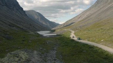 Khibiny Dağları vadisinde toprak bir yolda arazi araçları sürüyor.
