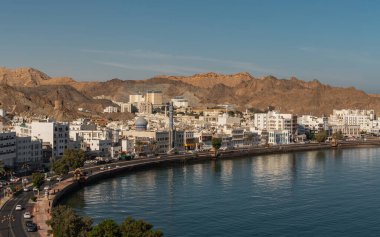 Mutrah Corniche 'in deniz kenarındaki gezinti alanı ve Muscat' taki kayalık tepeler manzarası